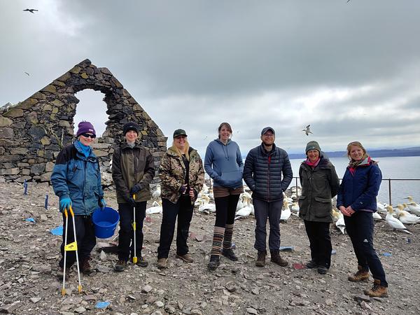 A team of seven people pose beside the old chapel on the Bass Rock, surrounded by nesting gannets and carrying tools