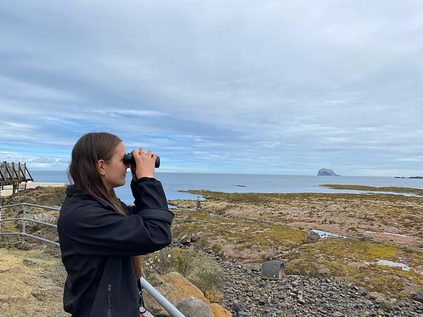 An onlooker scanning the rocks at North Berwick through a set of binoculars, with the Bass Rock in the background